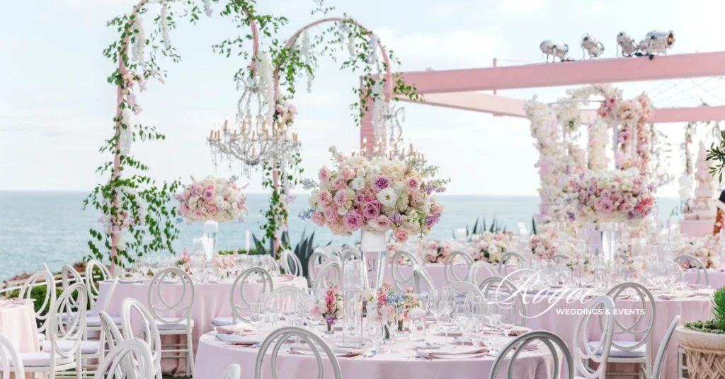 Wide shot of oceanfront reception with chandeliers and soft blush tablescape at a luxury Montage Laguna Beach wedding